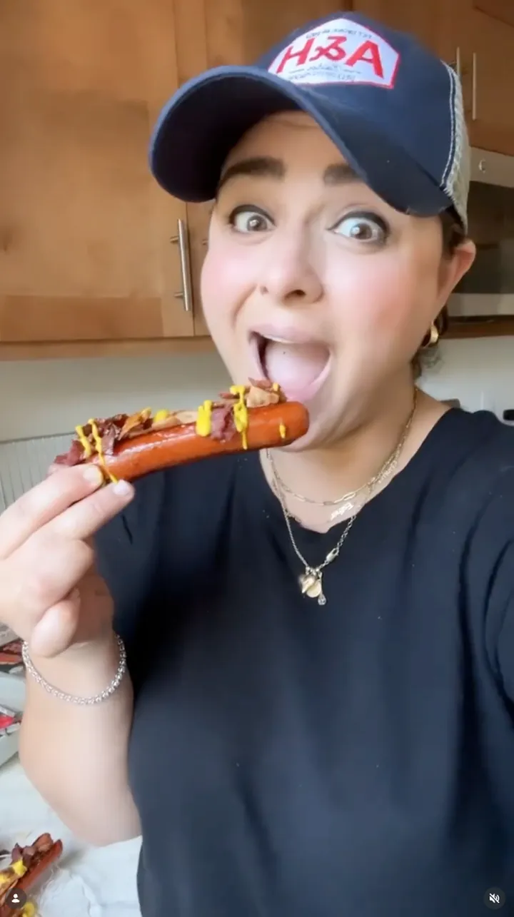 Abeles & Heymann creator taking a first bite of a hot dog